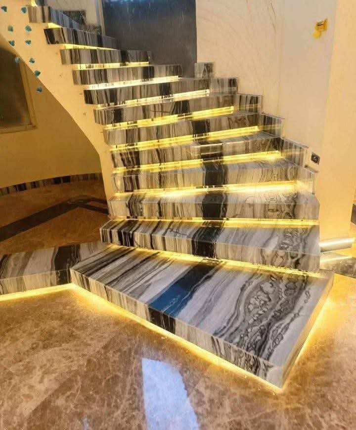 درج رخامي بعروق رمادية وسوداء متموّجة مع إضاءة LED أسفل كل درجة